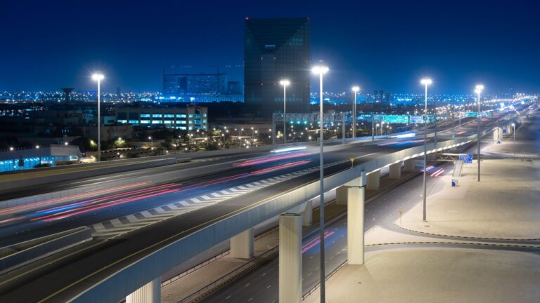 A vibrant urban landscape featuring a lit highway and towering buildings at night.